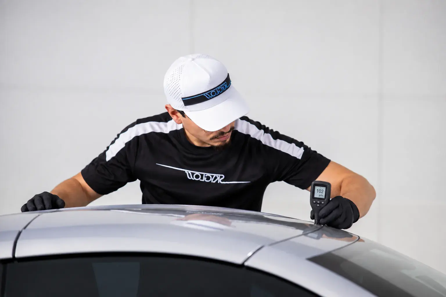 A SkyGloss technician measuring paint thickness on a vehicle