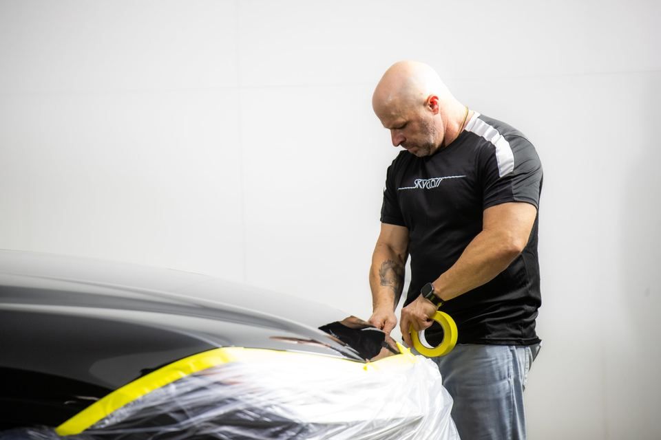 A technician masking a car before application
