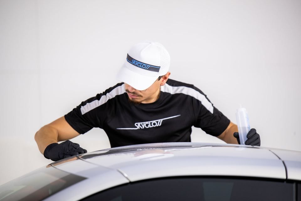A technician working across a car roof